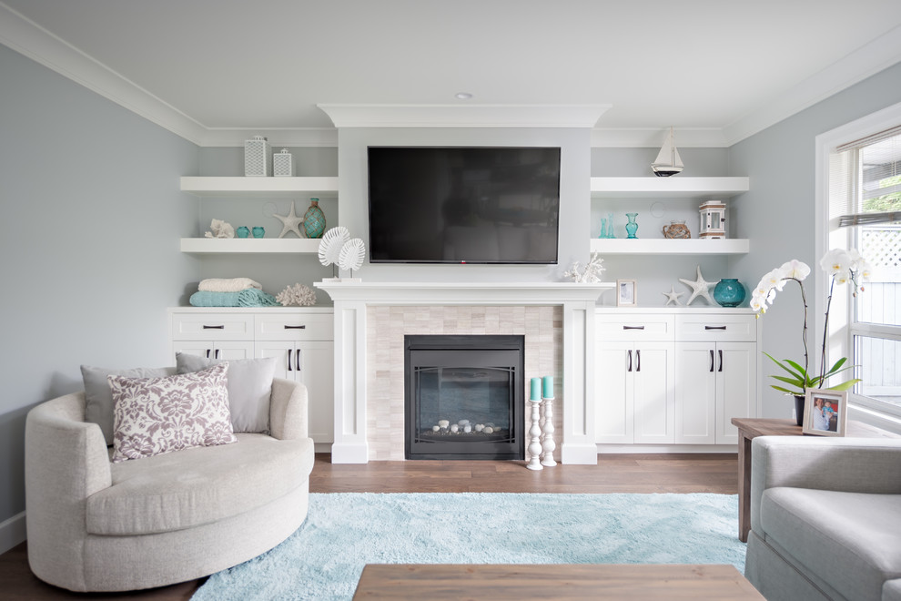 Inspiration for a mid-sized beach style family room in Vancouver with grey walls, a standard fireplace, a stone fireplace surround, a built-in media wall and dark hardwood floors.
