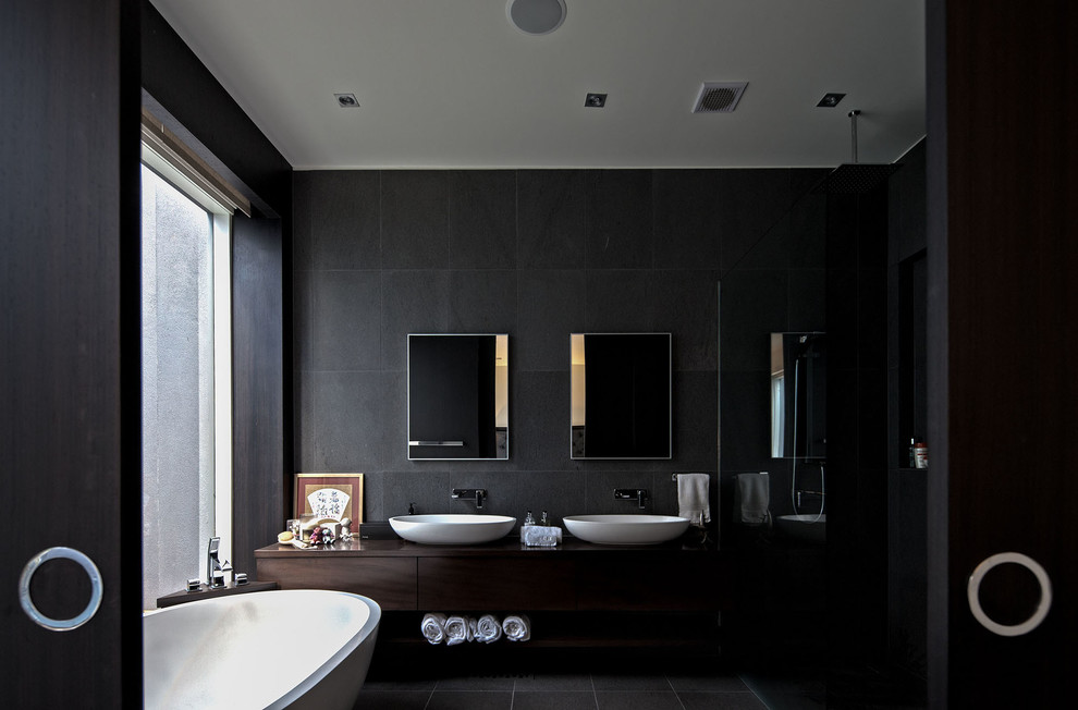 This is an example of a large contemporary master bathroom in Melbourne with furniture-like cabinets, dark wood cabinets, a freestanding tub, an open shower, a wall-mount toilet, gray tile, stone tile, grey walls, marble floors, a console sink, wood benchtops, grey floor, an open shower and brown benchtops.