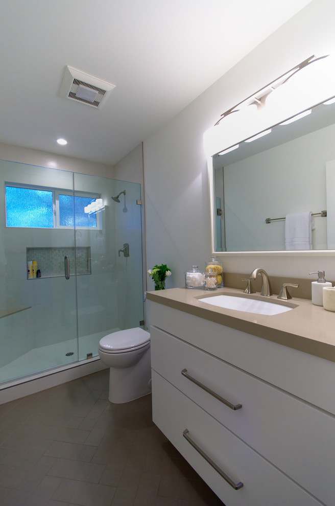Inspiration for a small transitional bathroom in San Francisco with flat-panel cabinets, white cabinets, a two-piece toilet, gray tile, porcelain tile, white walls, porcelain floors, an undermount sink and engineered quartz benchtops.