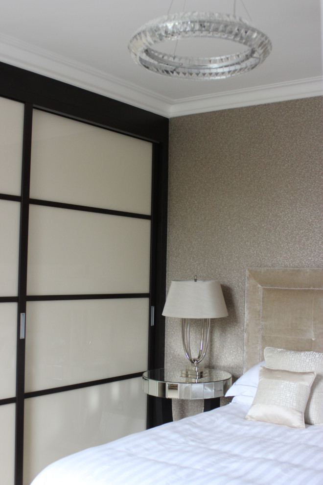 Inspiration for a mid-sized traditional master bedroom in Surrey with beige walls, carpet, beige floor and wallpaper.