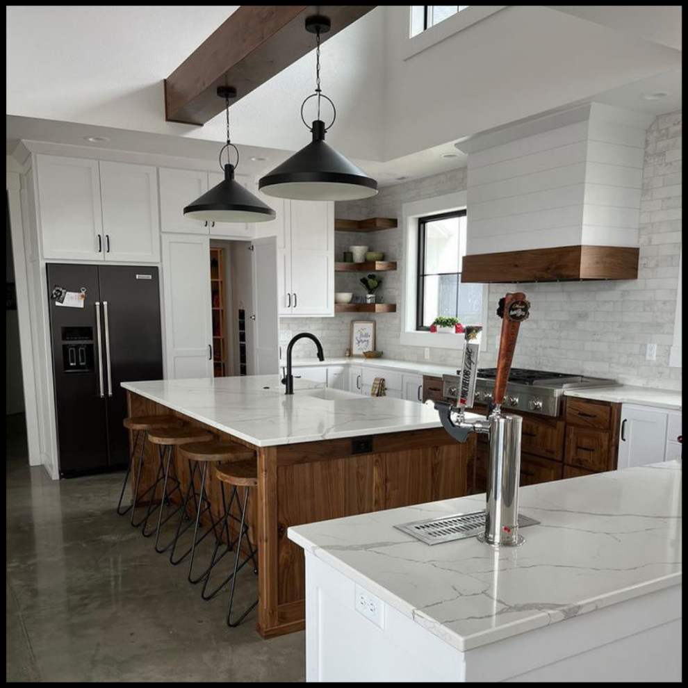 Mountain style kitchen photo with white cabinets, white backsplash, black appliances, an island and white countertops