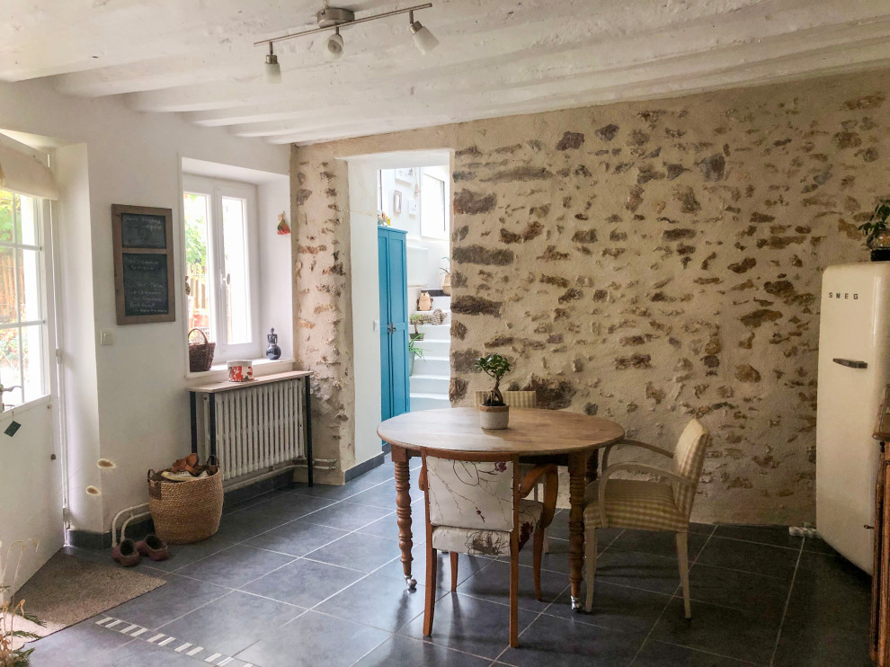 Idée de décoration pour une salle à manger ouverte sur le salon champêtre de taille moyenne avec un mur beige, un sol en carrelage de céramique, aucune cheminée, un sol noir et poutres apparentes.