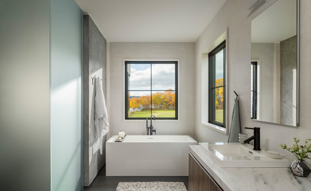 This is an example of a large country master wet room bathroom in Burlington with flat-panel cabinets, dark wood cabinets, a freestanding tub, white tile, porcelain tile, porcelain floors, a vessel sink, marble benchtops, grey floor, a sliding shower screen, white benchtops and beige walls.