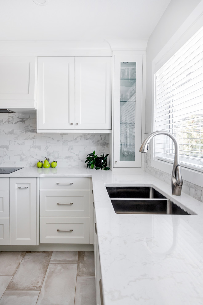 Inspiration for a mid-sized transitional u-shaped porcelain tile and beige floor eat-in kitchen remodel in Edmonton with a double-bowl sink, shaker cabinets, white cabinets, quartz countertops, multicolored backsplash, subway tile backsplash, stainless steel appliances, an island and white countertops