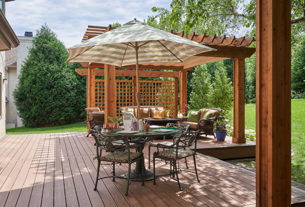 This is an example of a traditional ground level deck in Minneapolis with a fire feature and a pergola.