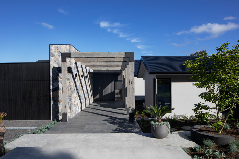 This is an example of a large and beige contemporary two floor detached house in Melbourne with mixed cladding, a pitched roof, a metal roof and a black roof.
