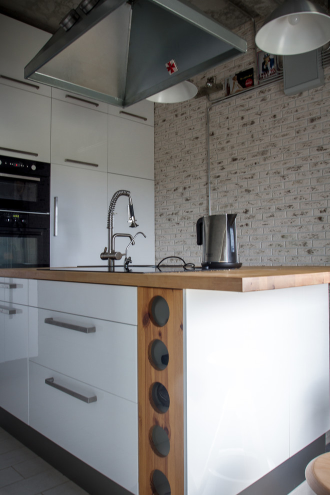 Photo of a medium sized enclosed kitchen in Saint Petersburg with a submerged sink, flat-panel cabinets, white cabinets, wood worktops, black appliances, ceramic flooring and an island.