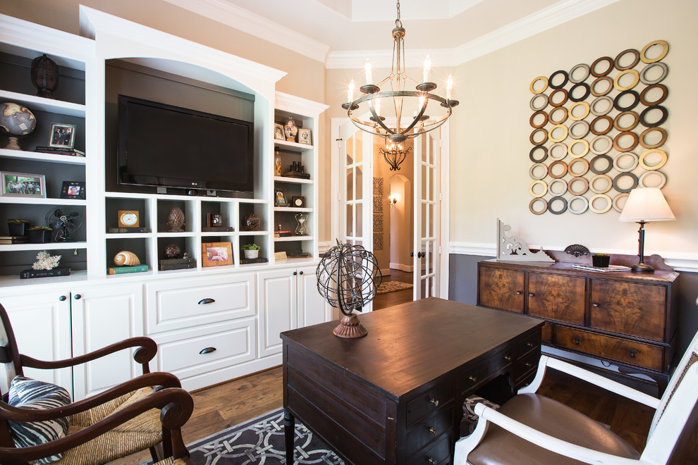 Traditional home office in Dallas with beige walls, dark hardwood floors and a freestanding desk.