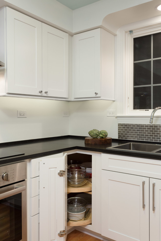 Mid-sized transitional u-shaped medium tone wood floor enclosed kitchen photo in Chicago with a double-bowl sink, white cabinets, quartzite countertops, gray backsplash, subway tile backsplash, stainless steel appliances, no island and shaker cabinets