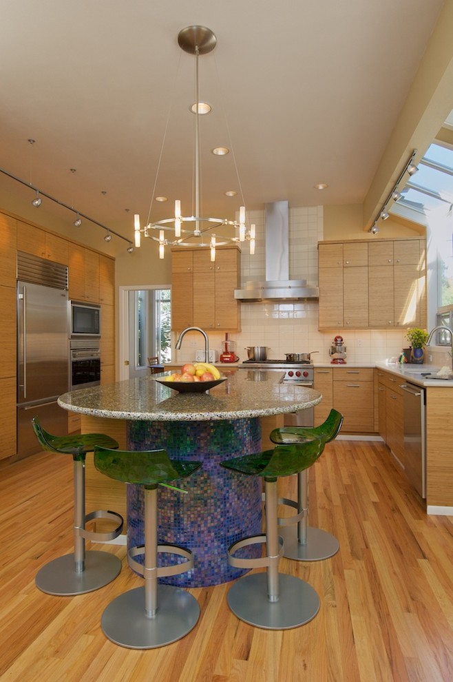 Photo of a contemporary l-shaped kitchen in Seattle with recycled glass benchtops, stainless steel appliances, flat-panel cabinets, medium wood cabinets, white splashback and subway tile splashback.