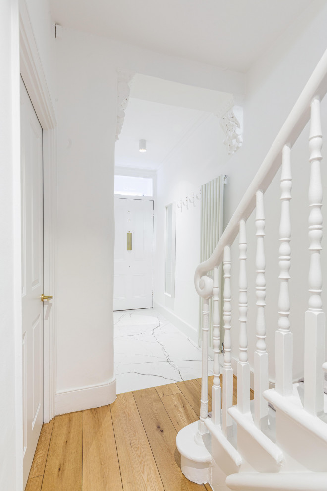 Inspiration pour un couloir minimaliste de taille moyenne avec un mur blanc, un sol en carrelage de porcelaine et un sol blanc.