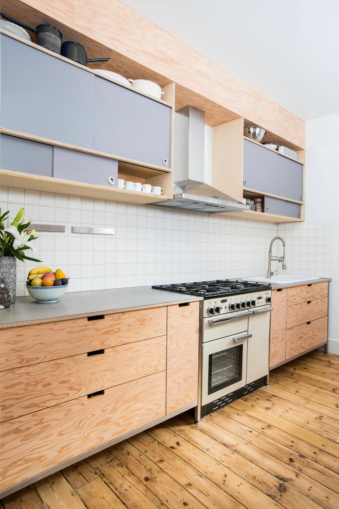 Design ideas for a mid-sized midcentury galley eat-in kitchen in London with flat-panel cabinets, stainless steel benchtops, white splashback, ceramic splashback, no island and white appliances.