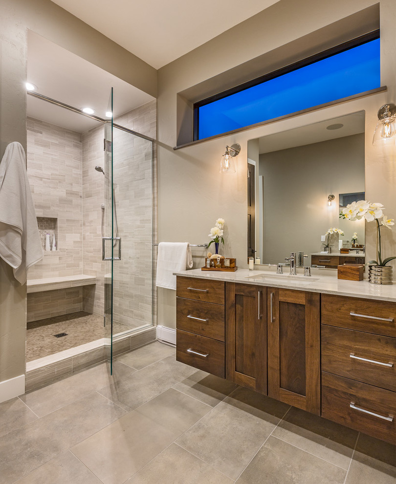Photo of a transitional master bathroom in Other with shaker cabinets, medium wood cabinets, a freestanding tub, beige tile, limestone, beige walls, ceramic floors, an undermount sink, quartzite benchtops and a hinged shower door.