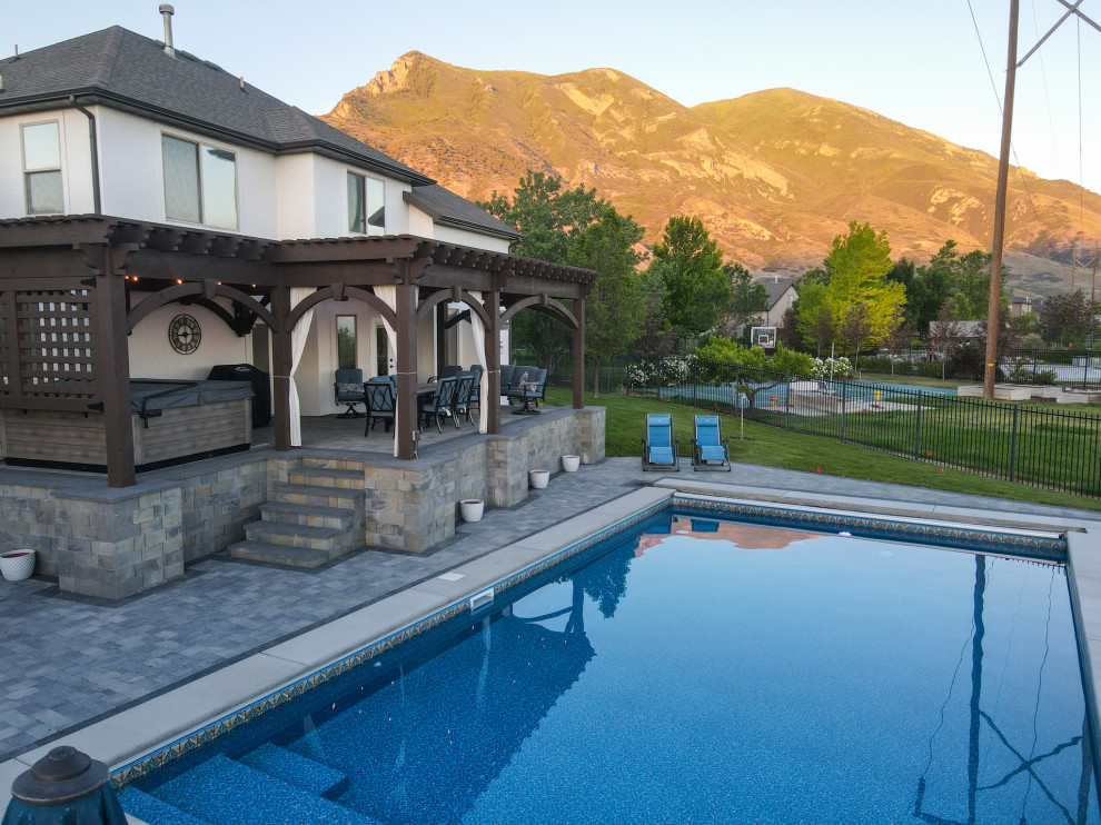 Modelo de piscina de estilo americano de tamaño medio a medida en patio trasero con paisajismo de piscina y adoquines de ladrillo