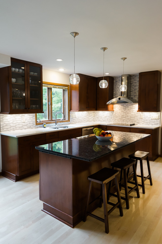 Large transitional l-shaped light wood floor eat-in kitchen photo with an undermount sink, shaker cabinets, dark wood cabinets, quartz countertops, gray backsplash, matchstick tile backsplash, stainless steel appliances and an island