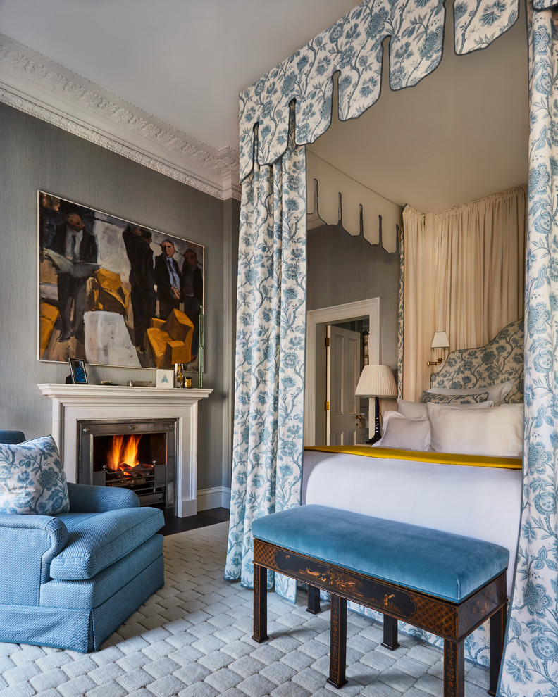 Photo of a traditional bedroom in London with blue walls, dark hardwood floors, a standard fireplace, a metal fireplace surround and brown floor.