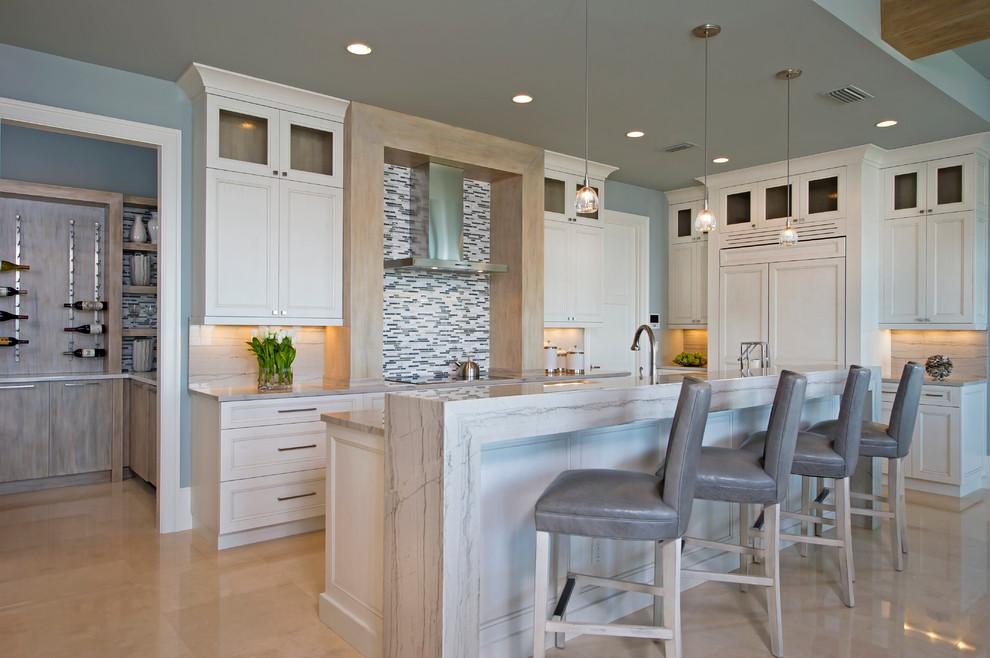 Design ideas for a mid-sized beach style single-wall eat-in kitchen in Orlando with recessed-panel cabinets, white cabinets, white splashback, matchstick tile splashback, panelled appliances, marble benchtops, marble floors, with island and beige floor.