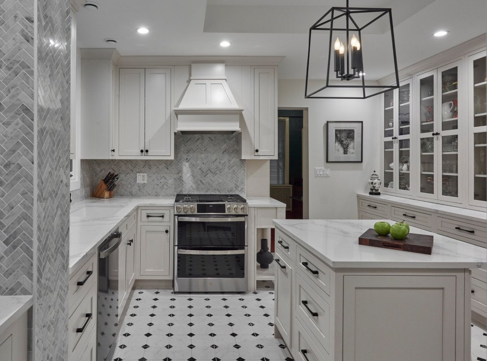 This is an example of a large traditional separate kitchen in Chicago with an undermount sink, recessed-panel cabinets, white cabinets, marble benchtops, grey splashback, porcelain splashback, black appliances, marble floors, with island, white floor and white benchtop.