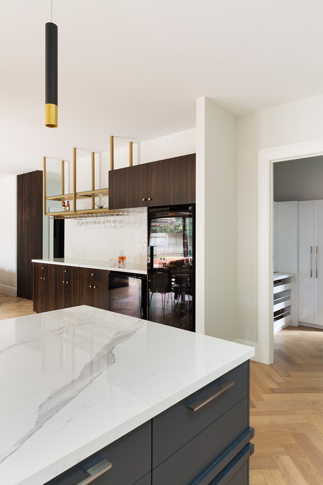 This is an example of a mid-sized contemporary single-wall wet bar in Melbourne with no sink, flat-panel cabinets, dark wood cabinets, tile benchtops, white splashback, glass tile splashback, light hardwood floors and brown floor.