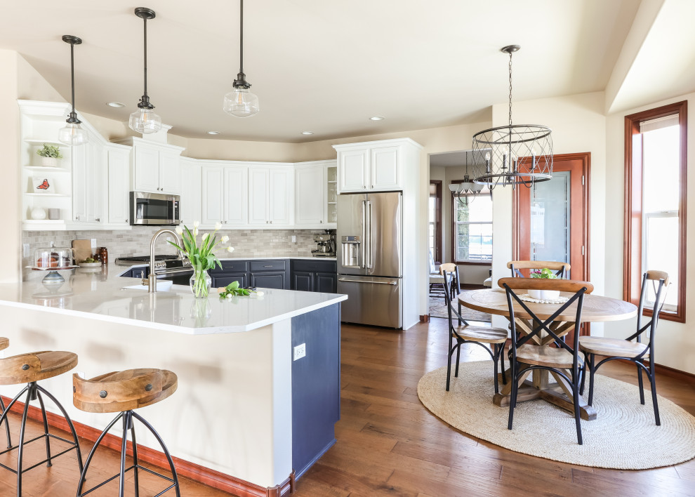 Inspiration for a mid-sized transitional u-shaped medium tone wood floor and brown floor kitchen remodel in Seattle with a farmhouse sink, white cabinets, quartz countertops, gray backsplash, marble backsplash, stainless steel appliances and white countertops