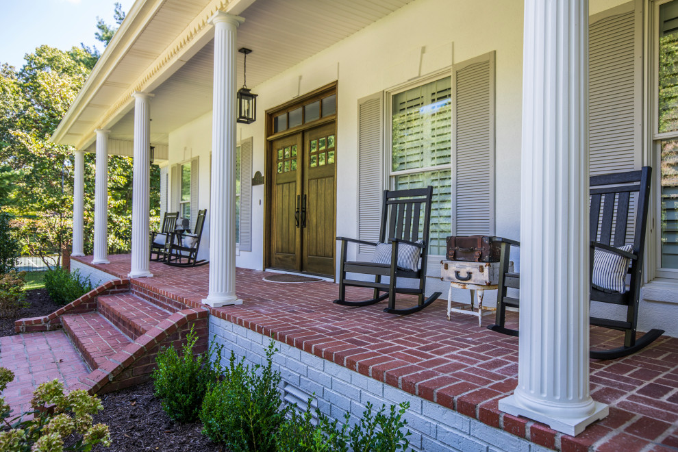 This is an example of a traditional front yard verandah in Other with brick pavers and a roof extension.