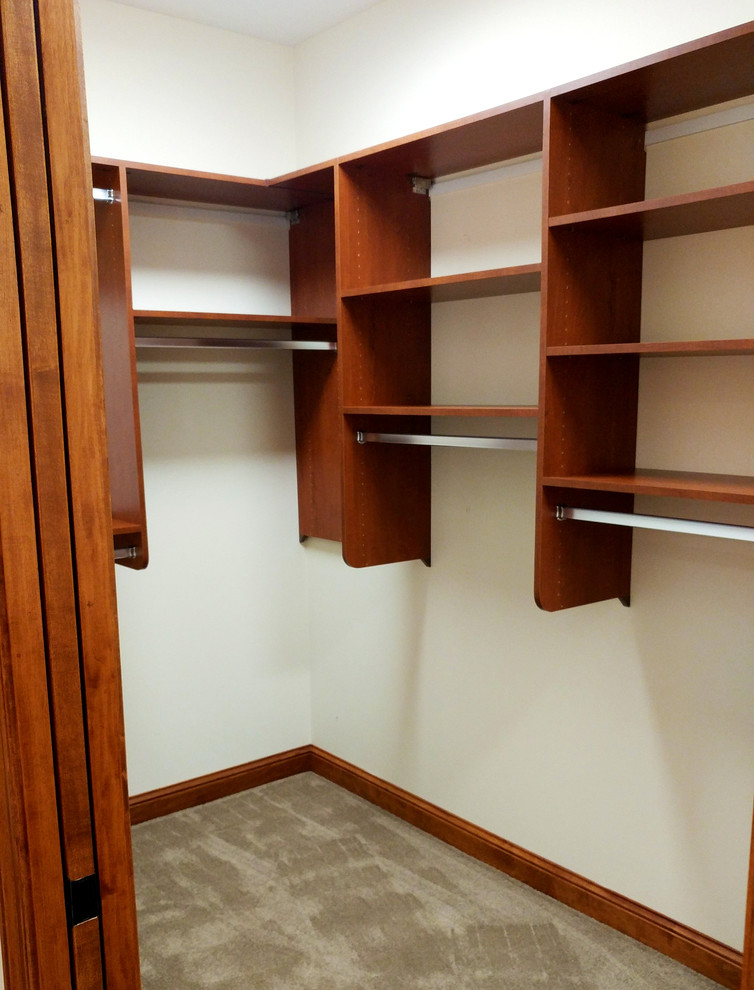 Photo of an expansive midcentury gender-neutral walk-in wardrobe in Milwaukee with flat-panel cabinets, medium wood cabinets, carpet and grey floor.