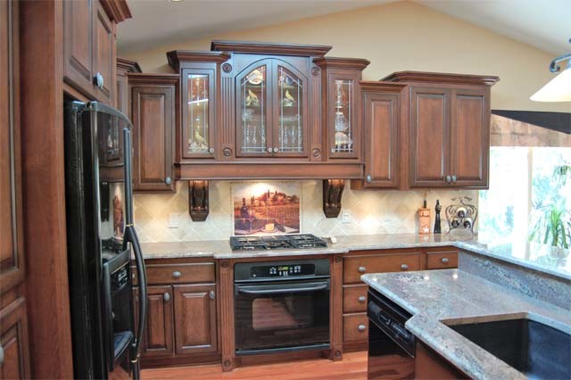 Photo of a mid-sized mediterranean l-shaped kitchen in Milwaukee with a drop-in sink, medium wood cabinets and granite benchtops.