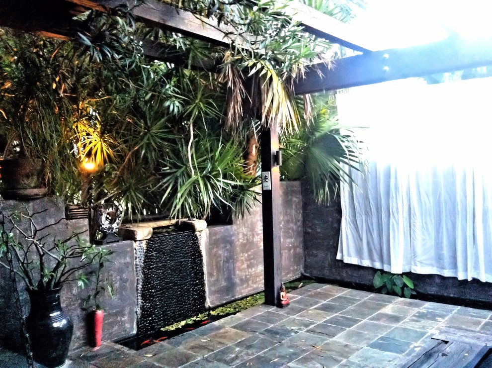 This is an example of a small asian front yard patio in Miami with a water feature, a pergola and tile.