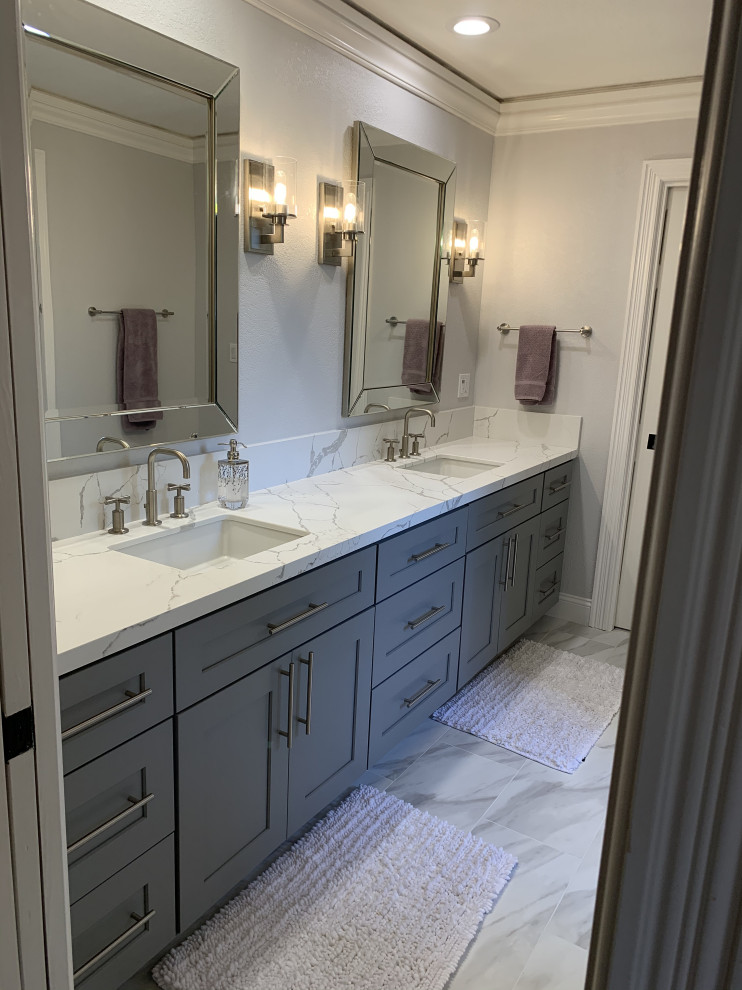 This is an example of a mid-sized contemporary kids bathroom in San Francisco with shaker cabinets, grey cabinets, a drop-in tub, a shower/bathtub combo, a one-piece toilet, white tile, porcelain tile, grey walls, porcelain floors, an undermount sink, engineered quartz benchtops, white floor, a sliding shower screen, white benchtops, an enclosed toilet, a double vanity, a built-in vanity and exposed beam.