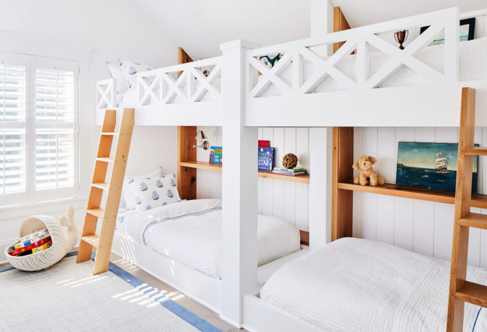 Photo of a mid-sized beach style gender-neutral kids' bedroom for kids 4-10 years old in New York with white walls, planked wall panelling, medium hardwood floors, vaulted and brown floor.