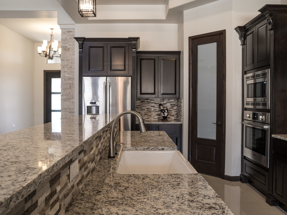 Inspiration for a mid-sized transitional galley marble floor eat-in kitchen remodel in Austin with a farmhouse sink, raised-panel cabinets, dark wood cabinets, granite countertops, brown backsplash, stone tile backsplash and no island