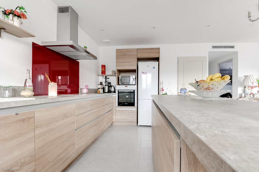 Small modern single-wall eat-in kitchen in Toulouse with a single-bowl sink, laminate benchtops, red splashback, glass sheet splashback, stainless steel appliances, ceramic floors, with island and beige floor.