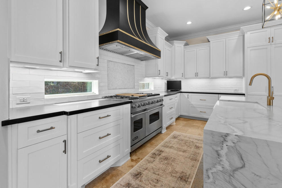 Example of a large transitional l-shaped limestone floor and beige floor eat-in kitchen design in Houston with a farmhouse sink, recessed-panel cabinets, white cabinets, quartzite countertops, white backsplash, limestone backsplash, stainless steel appliances, an island and white countertops