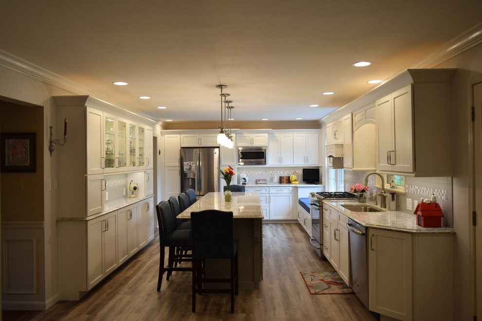 Inspiration for a huge transitional medium tone wood floor and brown floor kitchen remodel with an undermount sink, shaker cabinets, white cabinets, quartz countertops, gray backsplash, subway tile backsplash, stainless steel appliances and an island