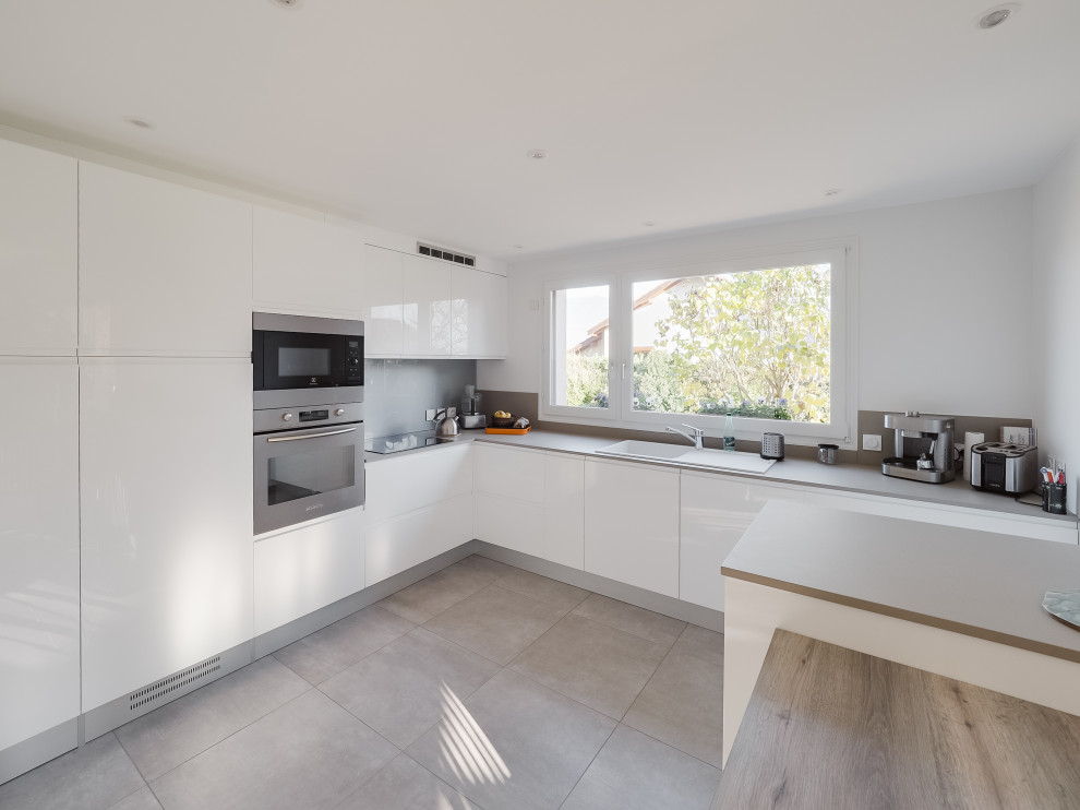 Design ideas for a large modern l-shaped open plan kitchen in Paris with white cabinets, laminate benchtops, grey splashback, timber splashback, ceramic floors, with island, beige floor and grey benchtop.