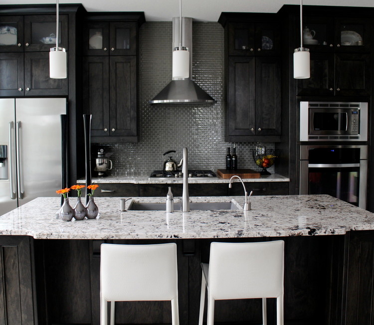 Example of a mid-sized transitional l-shaped open concept kitchen design in Calgary with an undermount sink, shaker cabinets, black cabinets, granite countertops, gray backsplash, mosaic tile backsplash, stainless steel appliances and an island