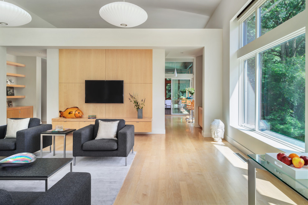 Foto di un grande soggiorno minimal con libreria, parquet chiaro, TV a parete e pavimento beige