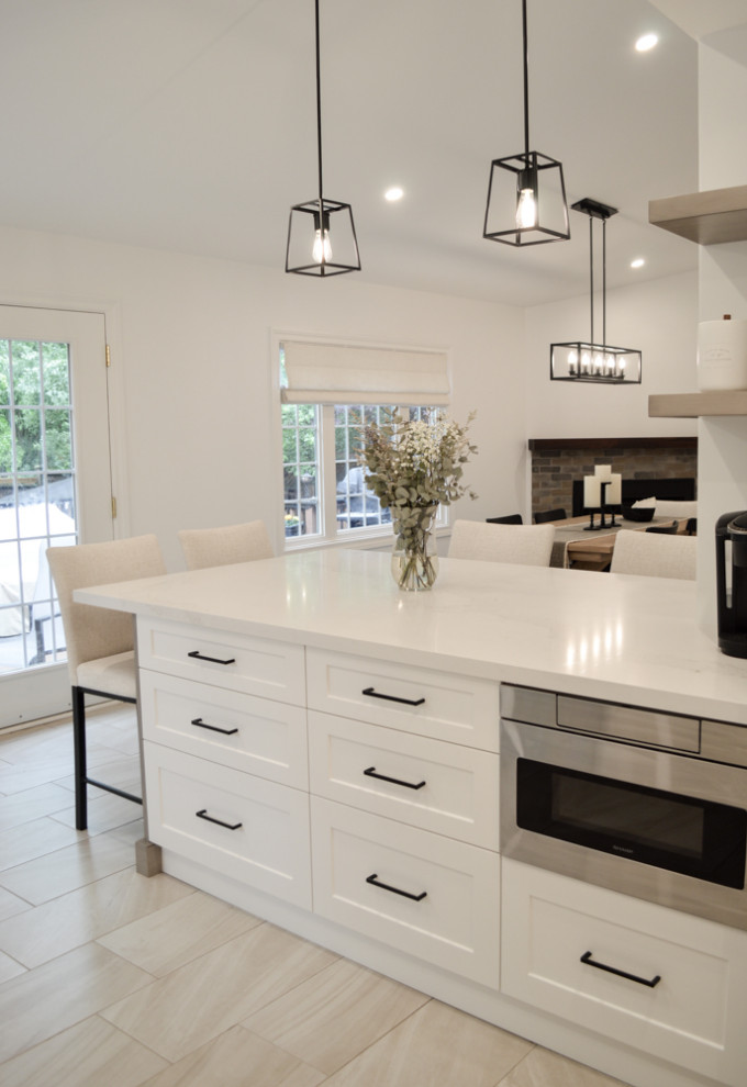 This is an example of a mid-sized contemporary u-shaped eat-in kitchen in Toronto with raised-panel cabinets, white cabinets, quartz benchtops, white splashback, porcelain splashback, stainless steel appliances, a peninsula, grey floor, white benchtop and vaulted.