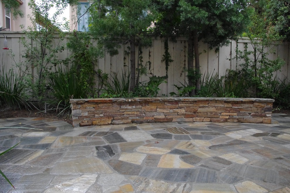 This is an example of a mid-sized arts and crafts front yard partial sun driveway in Orange County with a retaining wall and concrete pavers.