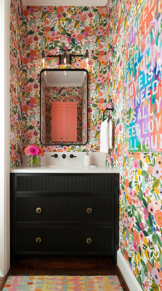 Inspiration pour un petit WC et toilettes vintage avec des portes de placard noires, un mur multicolore, parquet foncé, un sol marron, un plan de toilette blanc, meuble-lavabo encastré et du papier peint.