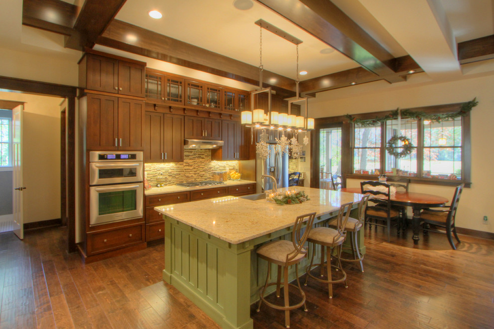 This is an example of a large arts and crafts eat-in kitchen in Atlanta with a single-bowl sink, shaker cabinets, dark wood cabinets, granite benchtops, glass tile splashback, stainless steel appliances, dark hardwood floors and with island.