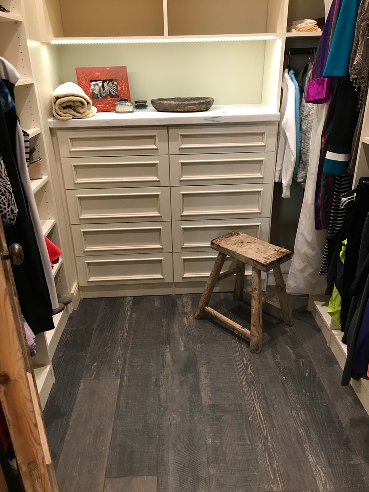 This is an example of a mid-sized mediterranean gender-neutral walk-in wardrobe in Phoenix with raised-panel cabinets, light wood cabinets, dark hardwood floors and brown floor.