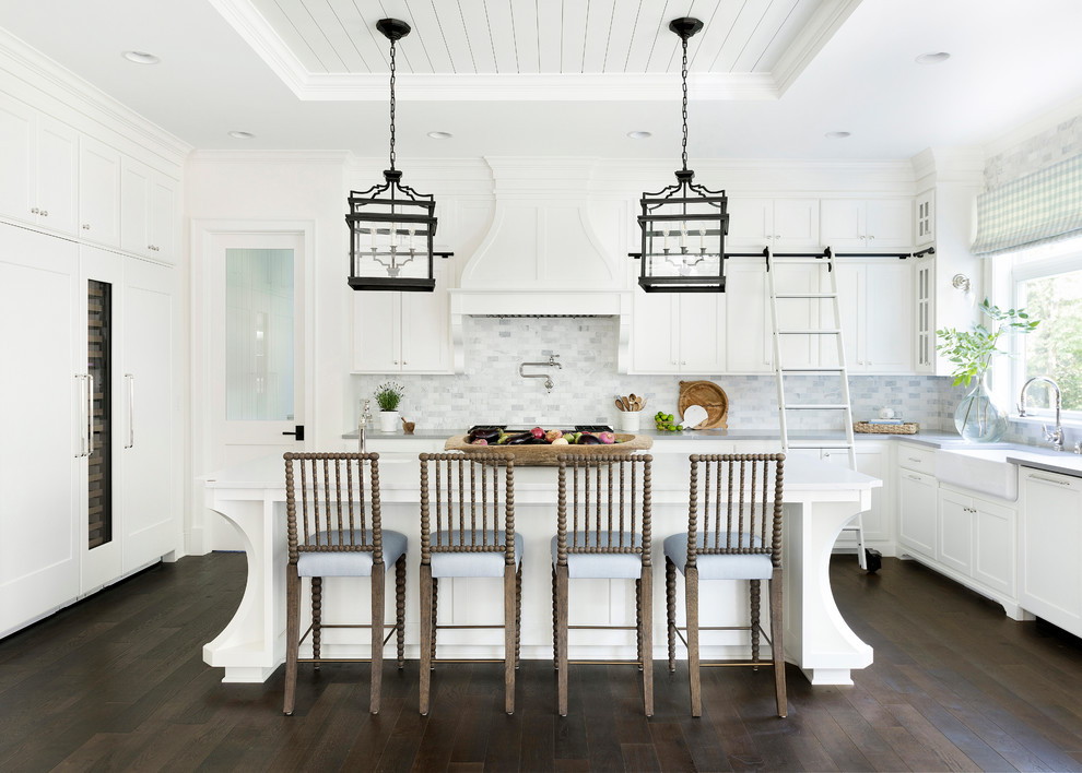 Inspiration for a large traditional l-shaped kitchen in Minneapolis with a farmhouse sink, shaker cabinets, white cabinets, marble splashback, panelled appliances, dark hardwood floors, with island, brown floor and grey splashback.