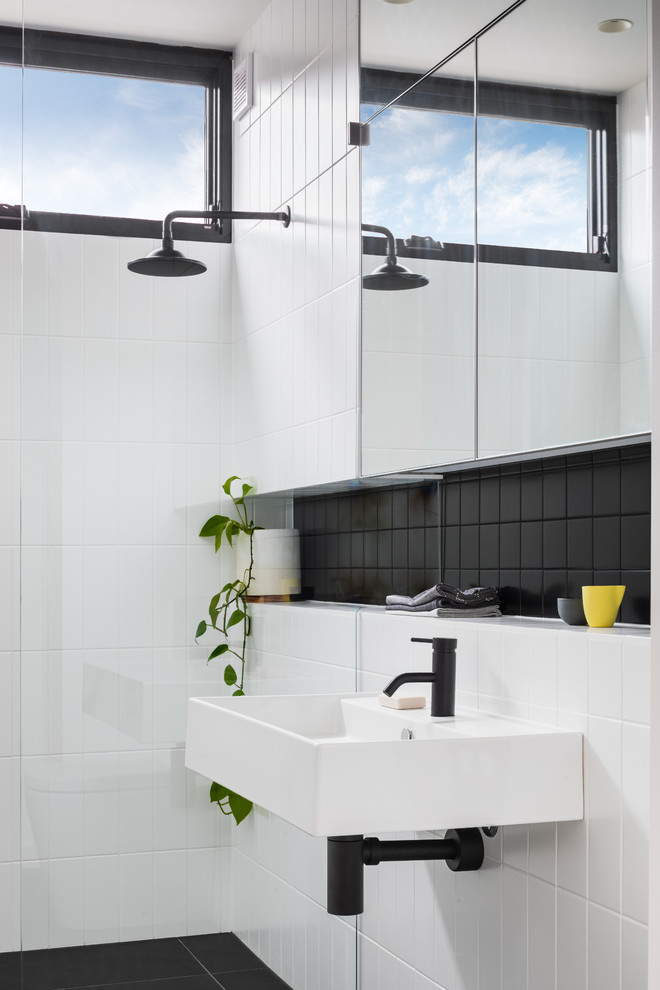 This is an example of a contemporary bathroom in Melbourne with an open shower, black tile, white tile, white walls, a wall-mount sink, black floor and an open shower.
