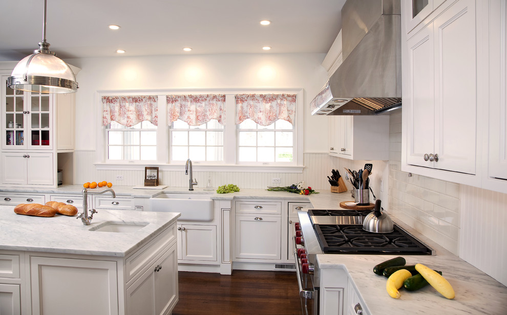 Inspiration for a mid-sized traditional u-shaped kitchen in New York with a farmhouse sink, beaded inset cabinets, white cabinets, marble benchtops, white splashback, subway tile splashback, stainless steel appliances, dark hardwood floors and with island.