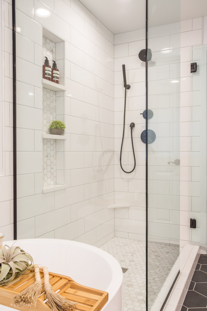 Photo of a mid-sized country master bathroom in Seattle with shaker cabinets, light wood cabinets, a freestanding tub, a corner shower, a one-piece toilet, white tile, subway tile, white walls, porcelain floors, an undermount sink, black floor, a hinged shower door, white benchtops and engineered quartz benchtops.