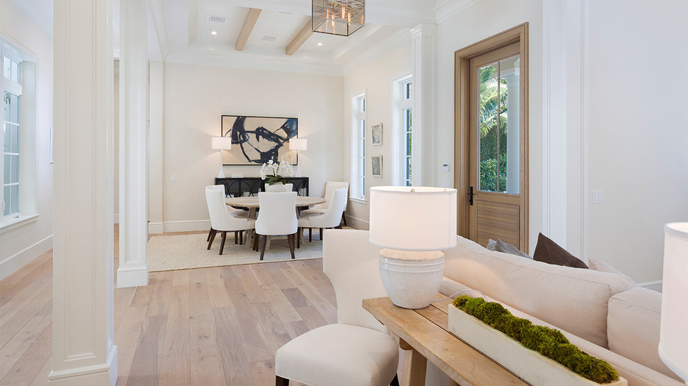 This is an example of a mid-sized tropical foyer in Miami with white walls, light hardwood floors, a single front door, a light wood front door and beige floor.