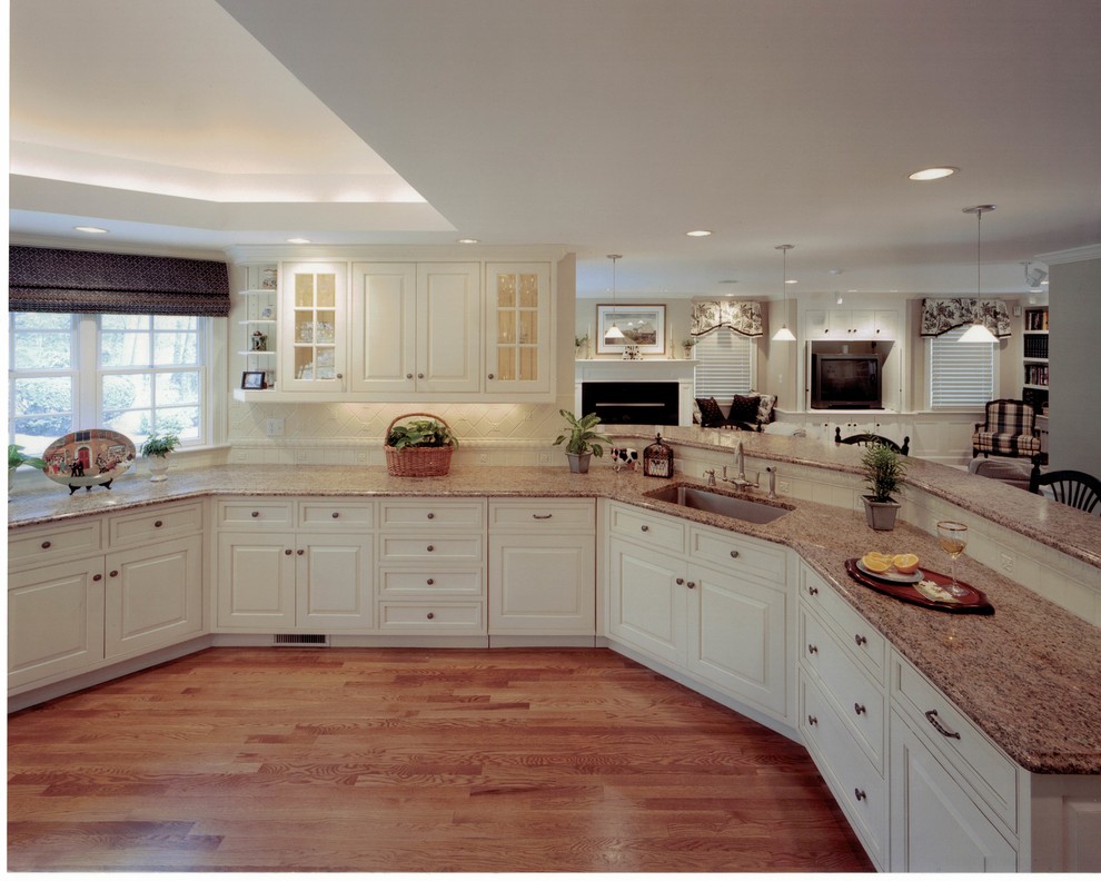 Photo of a large traditional u-shaped separate kitchen in Boston with an undermount sink, raised-panel cabinets, white cabinets, granite benchtops, white splashback, stainless steel appliances, medium hardwood floors, with island and brown floor.