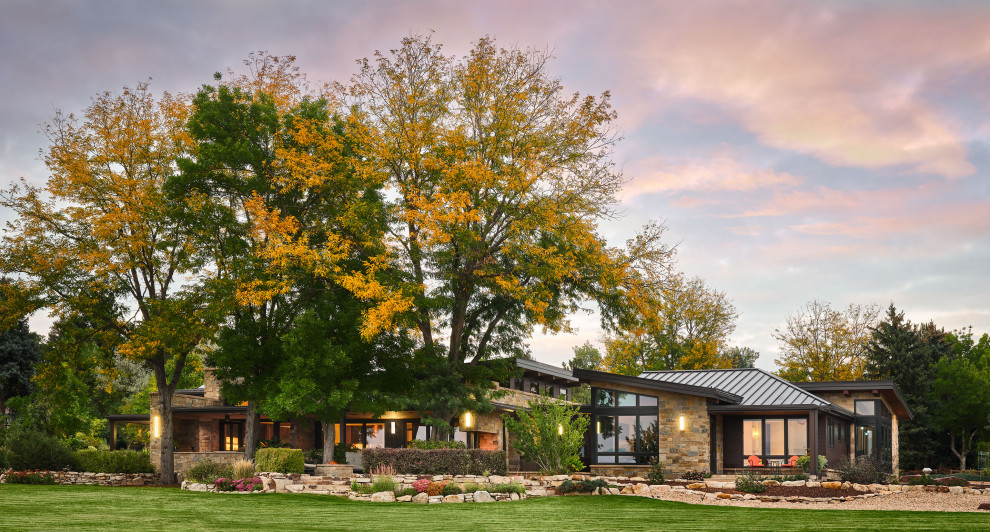 Inspiration for a large contemporary brown one-story stone house exterior remodel in Denver with a metal roof and a brown roof