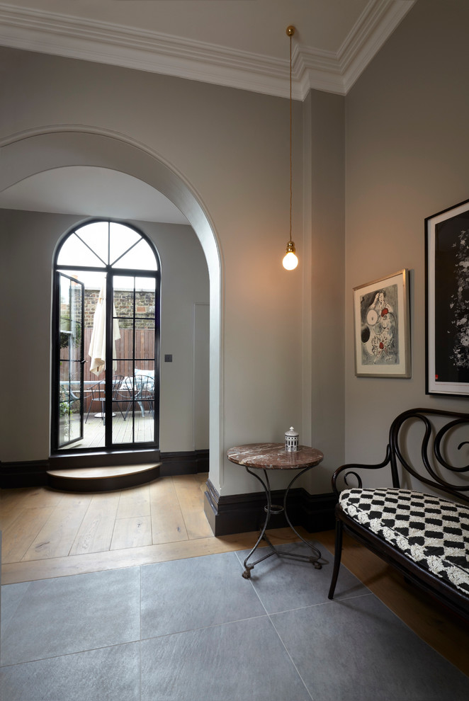 Photo of a transitional entry hall in London with grey walls and a double front door.